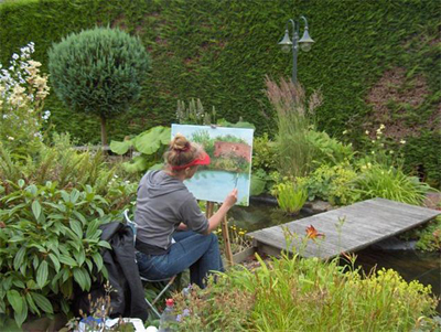 Margo schildert in een tuin.